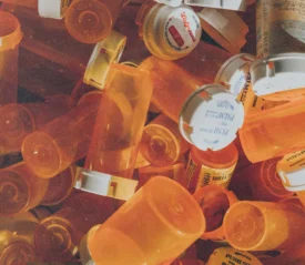 A scattered pile of empty orange prescription bottles with white caps, filling the entire frame
