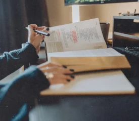 A person studies at a desk with an open Bible, highlighting passages while writing notes in a notebook