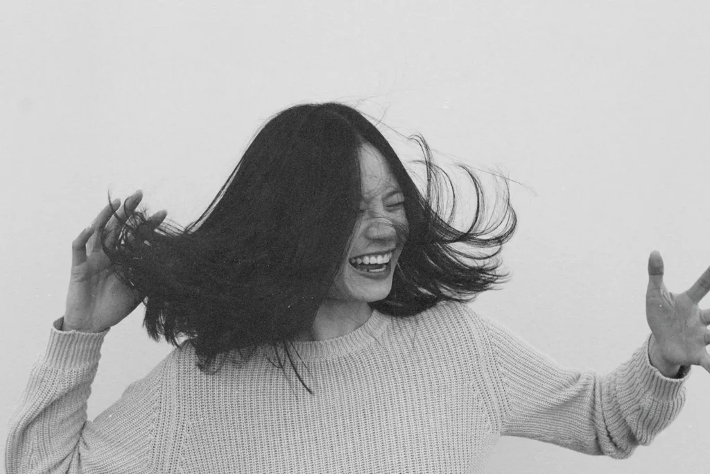 Person tossing their hair while wearing a textured knit sweater against a plain background