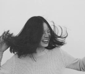 Person tossing their hair while wearing a textured knit sweater against a plain background