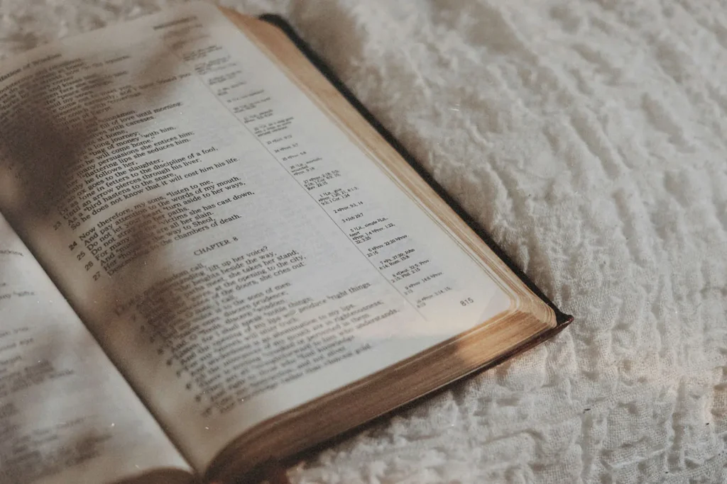 Close-up of an open Bible laid on a white, patterned fabric surface with gentle shadows
