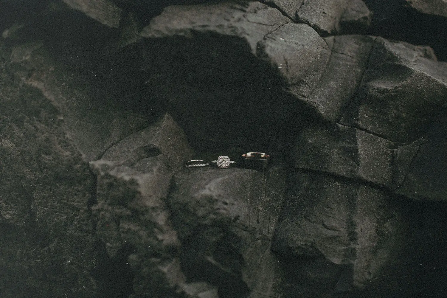 Two wedding rings resting on dark, textured volcanic rocks