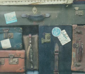 Collection of old-fashioned suitcases stacked tightly together, some decorated with vintage travel stickers