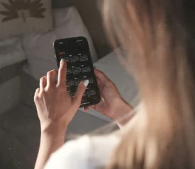 A person uses a smartphone, tapping on a full-year calendar displayed on the screen