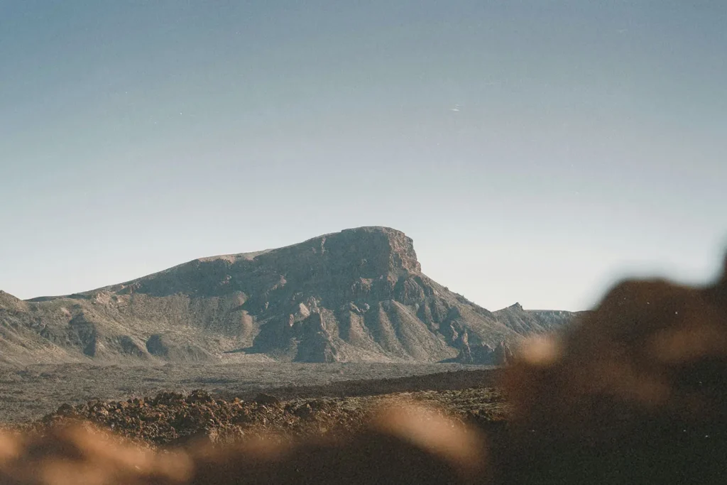 Large mesa standing in an open desert landscape under bright, cloudless skies