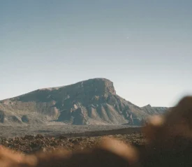 Large mesa standing in an open desert landscape under bright, cloudless skies