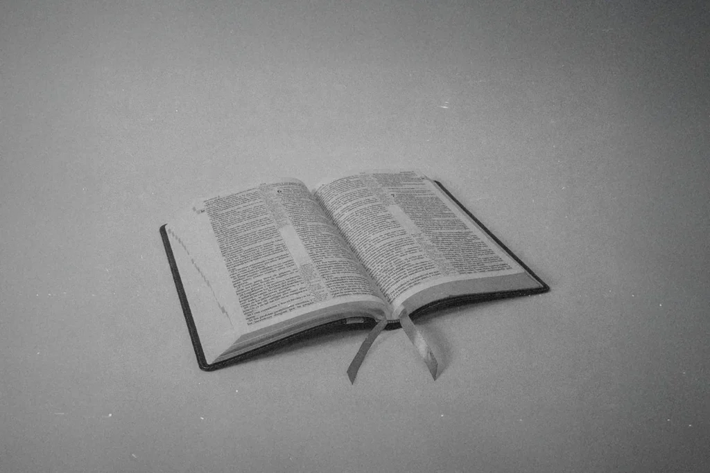 Open Bible resting on a flat surface with ribbon markers lying across the pages