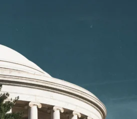 White domed government building with classical columns beneath a clear blue sky