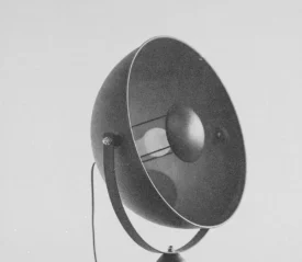 Vintage amplifier horn with a round metal housing against a plain background