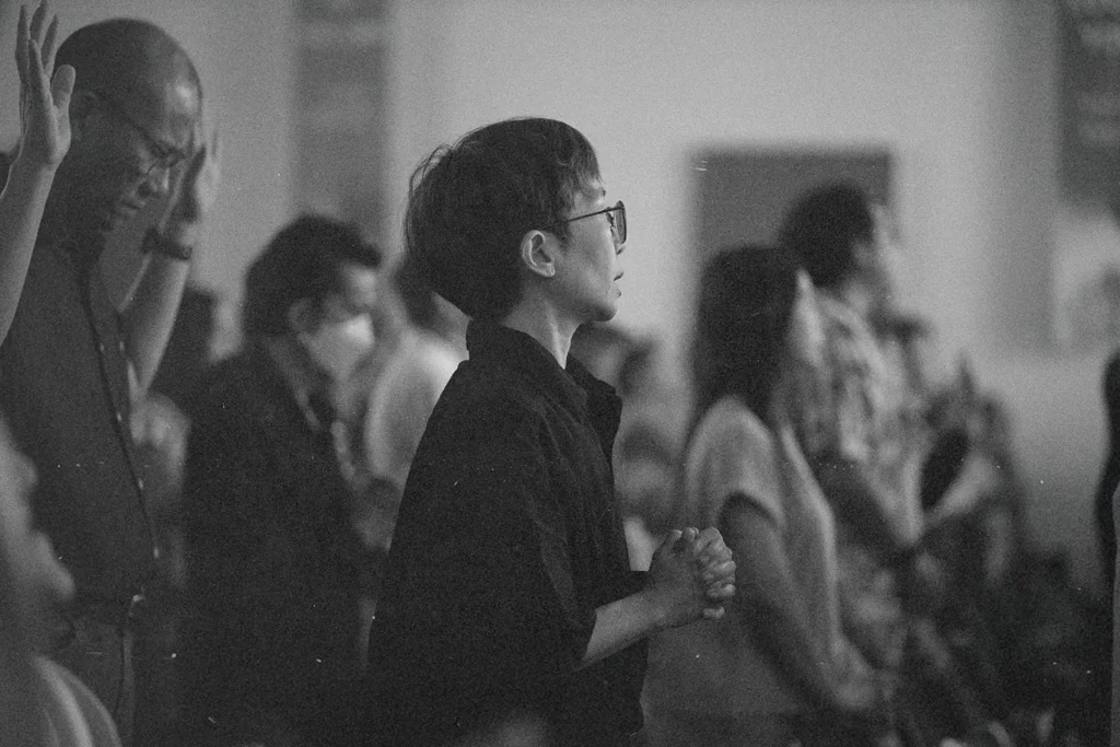 Crowd of people engaged in worship, with hands lifted and bodies turned toward the front