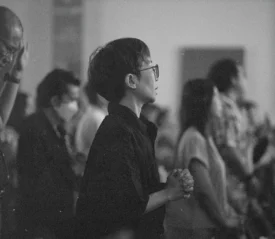 Crowd of people engaged in worship, with hands lifted and bodies turned toward the front