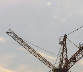 Construction cranes silhouetted against a soft evening sky with light clouds