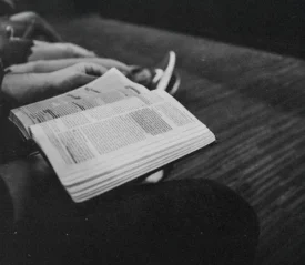 Person holding an open Bible while seated in a quiet setting