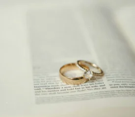 Two gold wedding rings, one with a diamond, rest on the open pages of a Bible