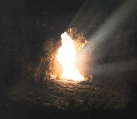 Sunlight streaming through the opening of a rocky cave, illuminating the stone floor with bright, warm rays