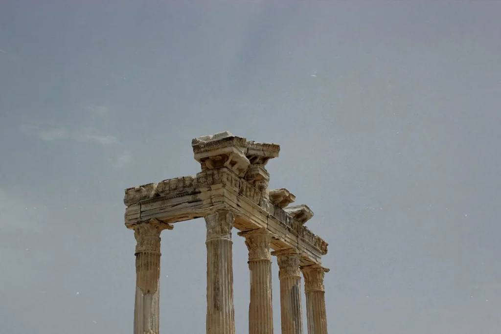 The upper portion of ancient stone columns stands against a pale sky, showcasing weathered classical architecture