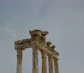 The upper portion of ancient stone columns stands against a pale sky, showcasing weathered classical architecture