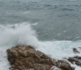 Waves crashing against rocks in the ocean, symbolizing staying strong in faith