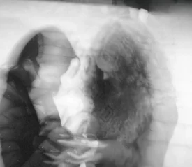 Two people sitting closely together in a soft, double‑exposed black‑and‑white image, creating a dreamy, motion‑blur effect