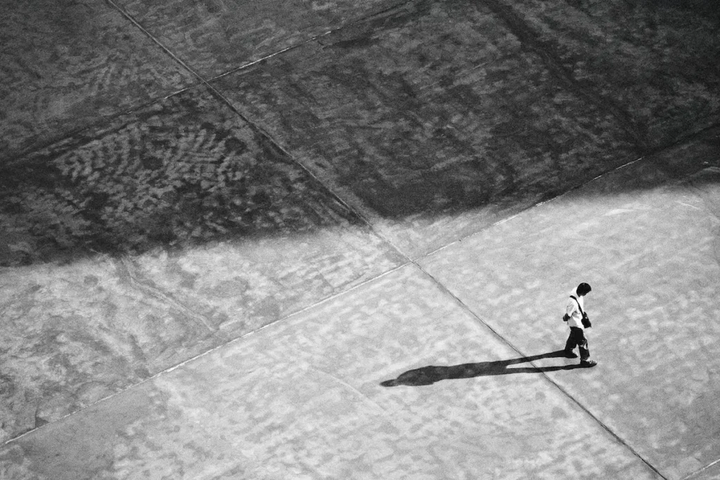 A man walking alone, casting a long shadow