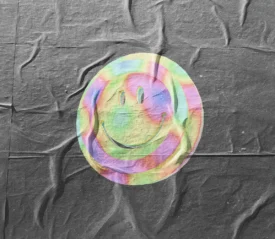 A colorful, iridescent smiley face graphic printed on a wrinkled dark fabric background