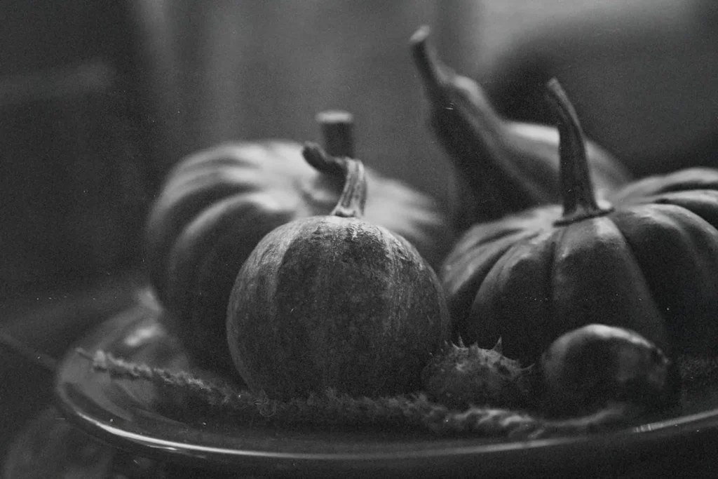 Black‑and‑white still life of assorted pumpkins and gourds arranged on a plate
