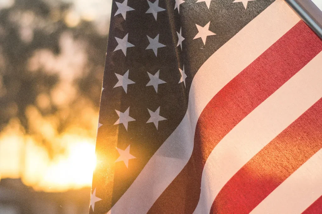 American flag waving outdoors with warm sunlight shining through at sunset