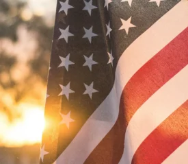 American flag waving outdoors with warm sunlight shining through at sunset