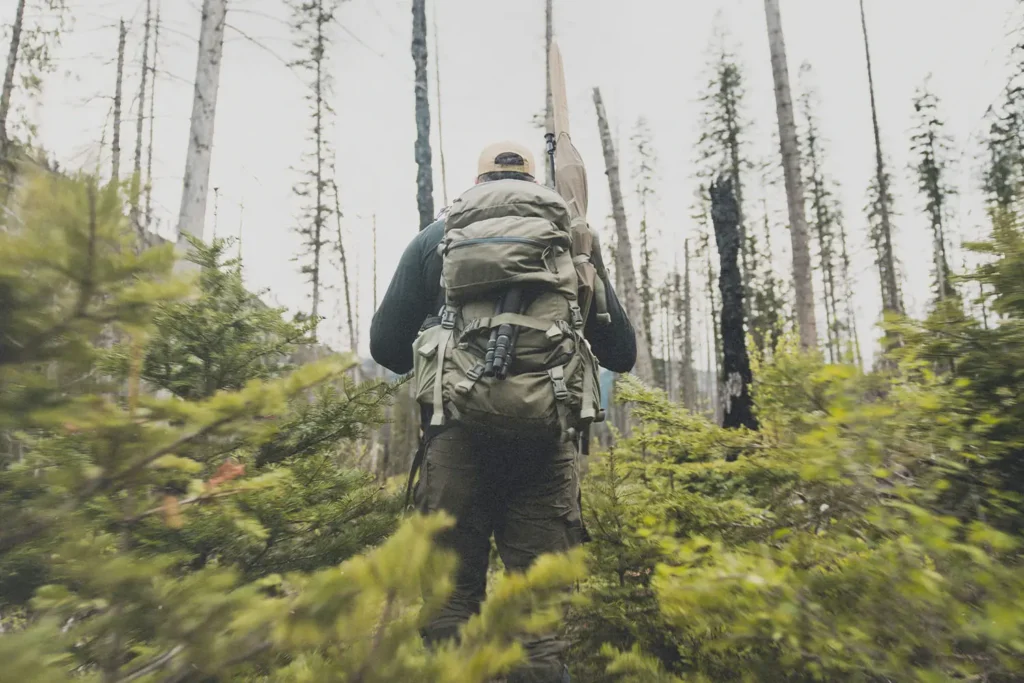 Man with backpack hiking uphill in a forest