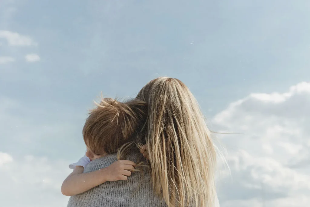 Blonde woman hugging young boy with blue sky background