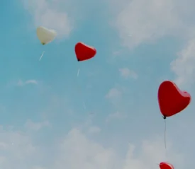 Red heart balloons flying through the sky