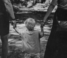 Little boy in the middle of two parents holding each hand