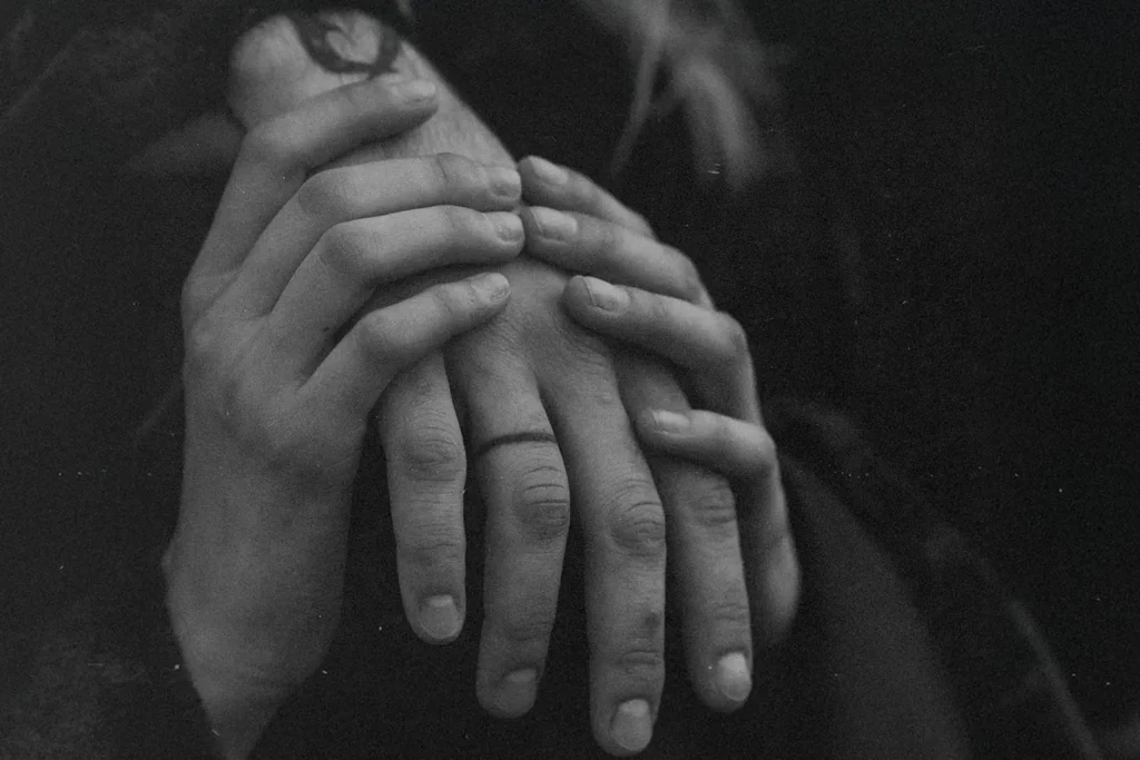 Close‑up of two people gently holding hands in a black‑and‑white scene