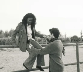 Man helping a woman get down from railing