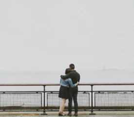 Couple standing at railing hugging each other