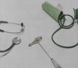 Stethoscope, blood pressure cuff, and reflex hammer arranged on a light surface