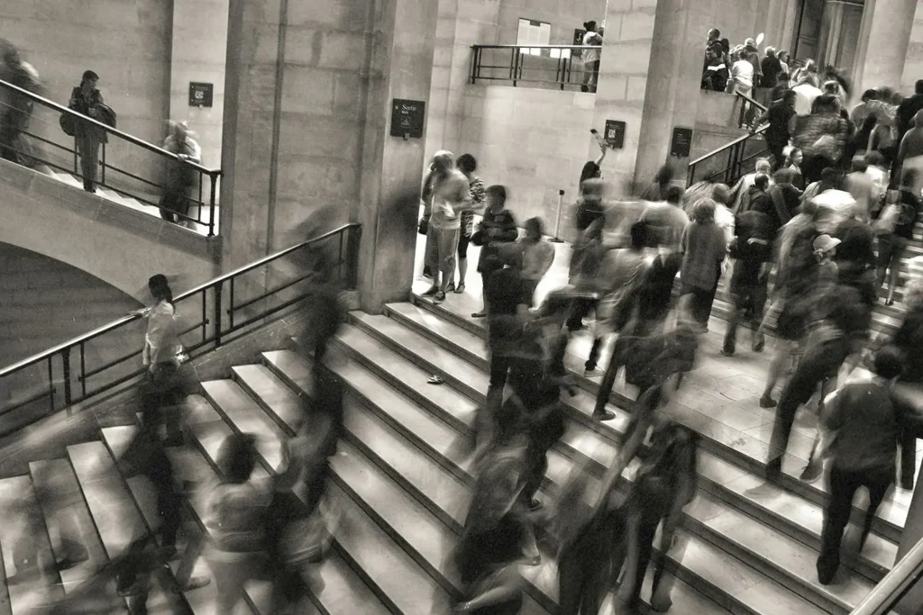 black and white photo of people walking up and down stairs in a busy scene