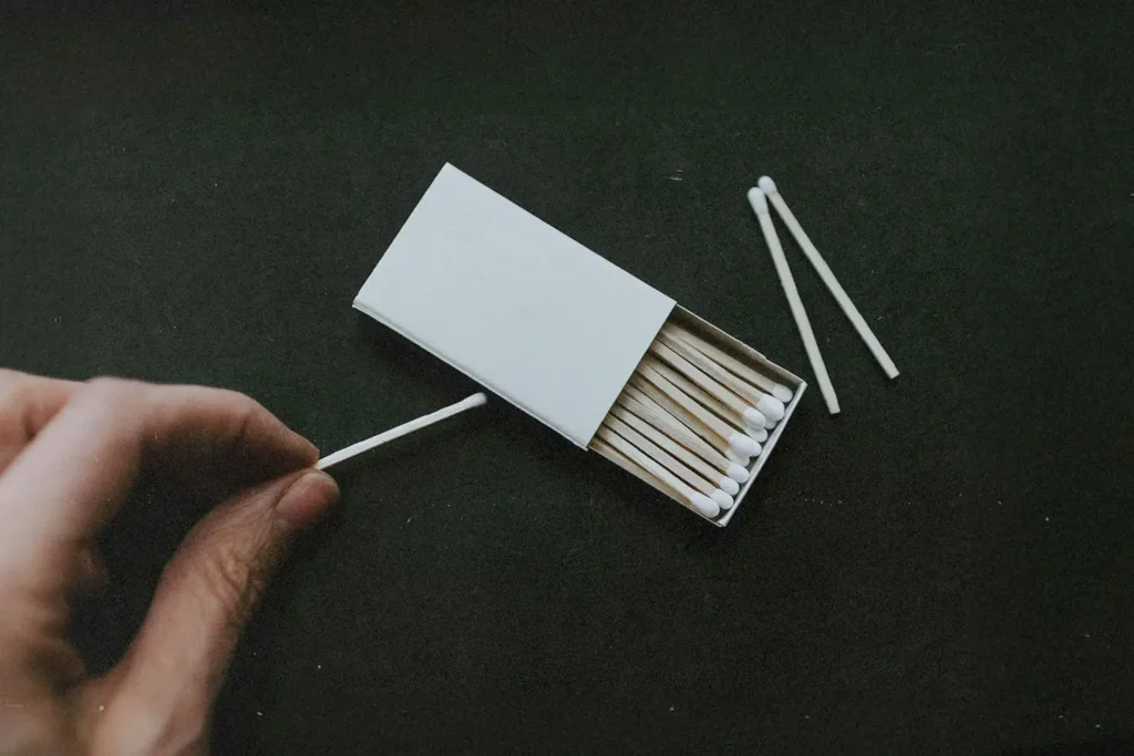 hand lighting a match with the match box