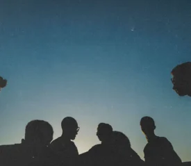 silhouette of people standing in front of a sunset