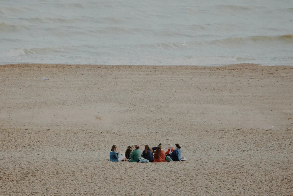 Friends gathered in a circle on a sandy beach near gentle ocean waves