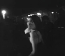 girl in shock running from camera in a darkroom filled with people