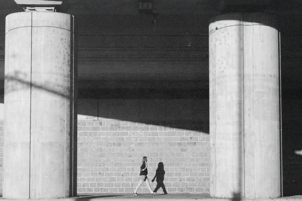 Woman walking through breezeway with two concrete pillars in view