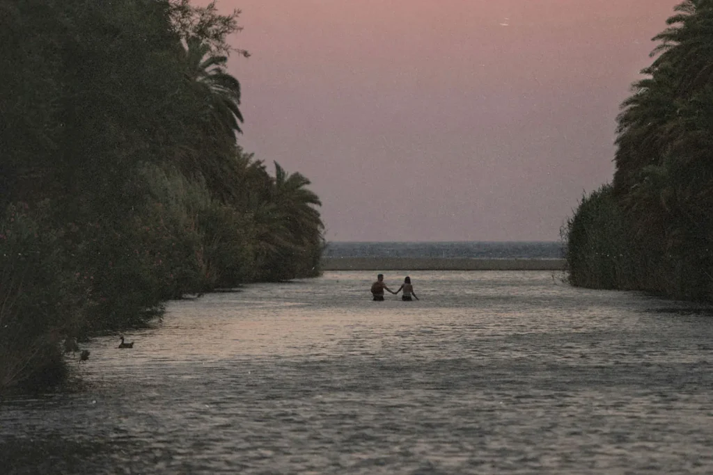 couple walking through water to the beach