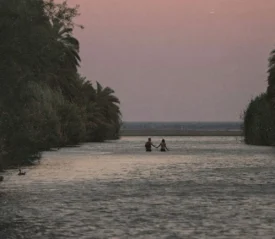 couple walking through water to the beach