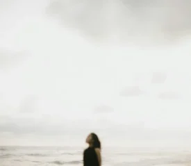 women on a beach looking up at a cloudy day