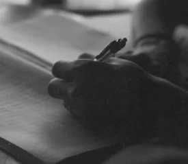 Close‑up of a hand writing in a notebook with soft lighting