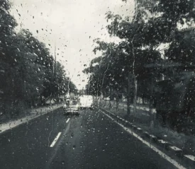 Raindrops on a clear window looking out to an open road
