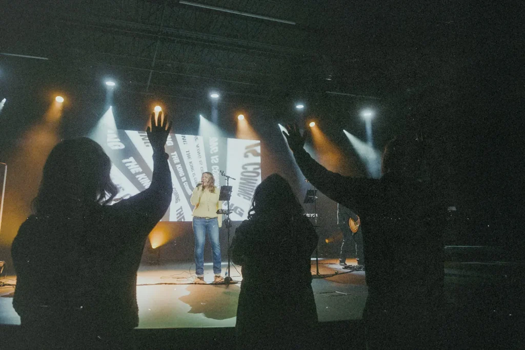 Worship band performing on stage with audience raising hands