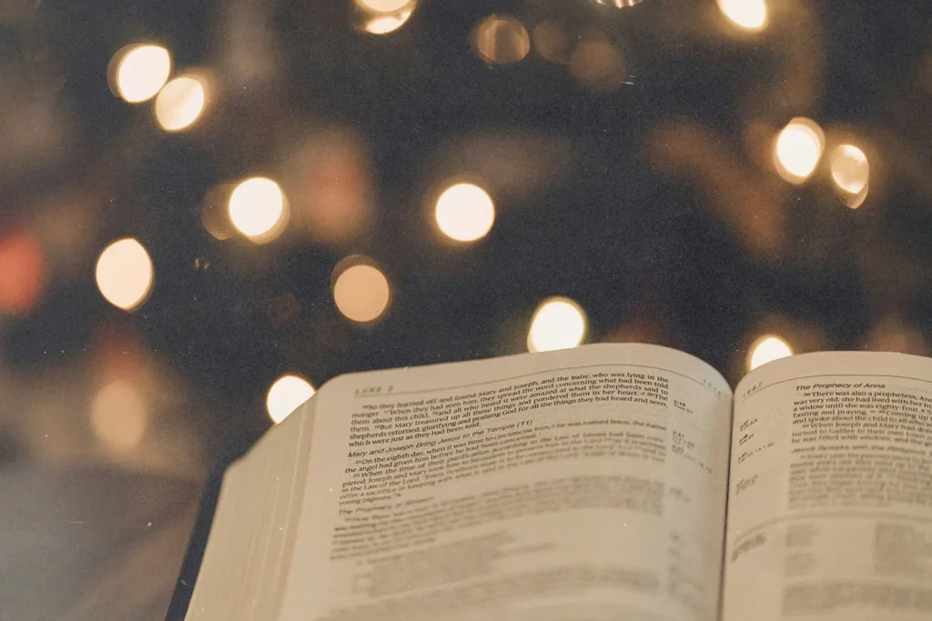 open bible in front of a lit christmas tree