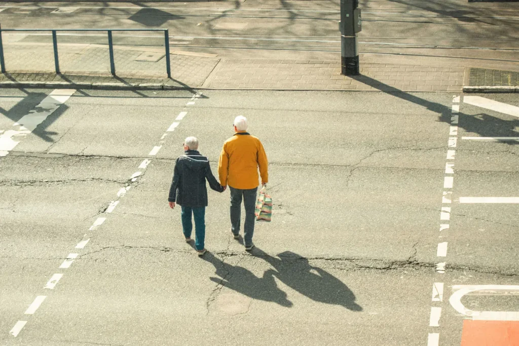 older couple holding hands walking across the street